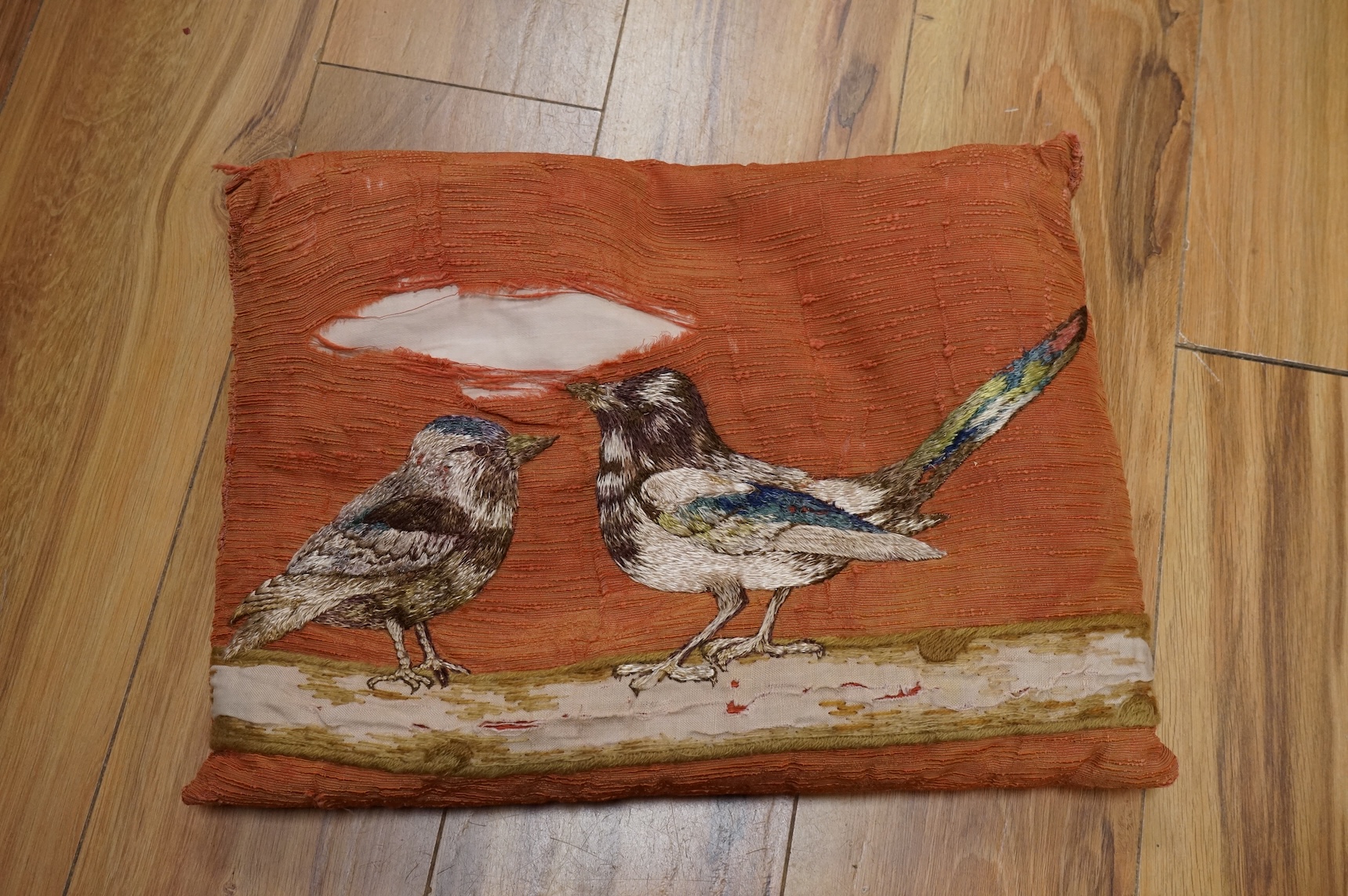 An Arts and Crafts embroidered table cover, an embroidered printed fabric sample later embroidered and a bird embroidered cushion.